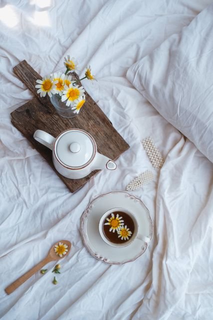 Chamomile tea arranged on a bed with flowers and wooden elements