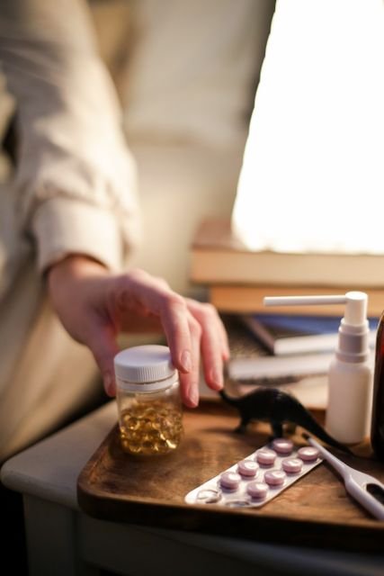 Hand reaching toward medicine and supplement containers on a nightstand