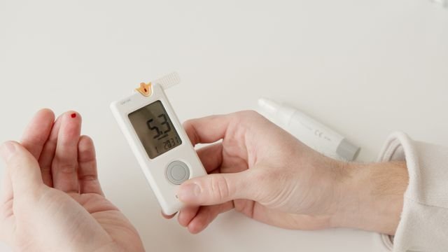 Hand using a glucometer to measure blood glucose