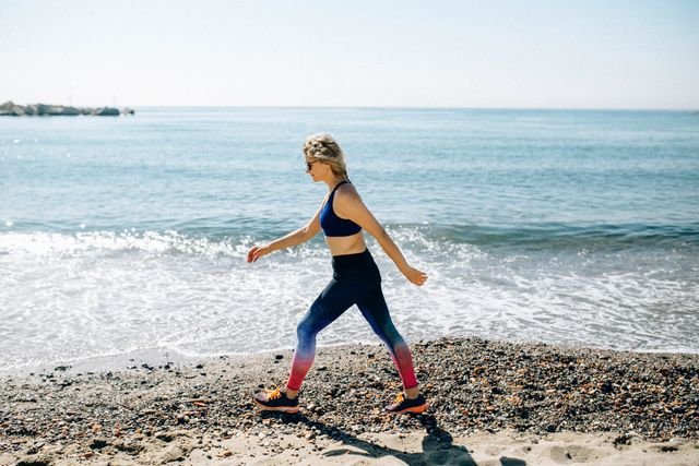 Woman power walking along a beach in activewear