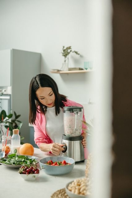 Woman preparing a smoothie with fresh fruits and greens