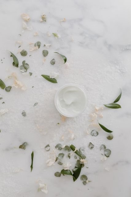 Open container of moisturizing cream on a marble surface