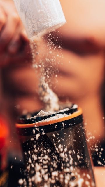 How Much Pre-Workout Should You Take? A Safer Guide to Serving Size, Caffeine, and Scoop Amount 5 Powdered fitness supplement being added to a shaker