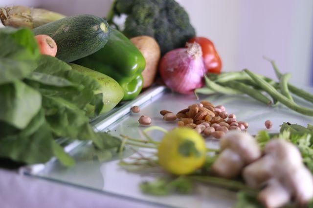 Fresh vegetables, leafy greens, nuts, and legumes arranged on a table