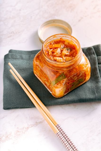 Jar of kimchi beside wooden chopsticks