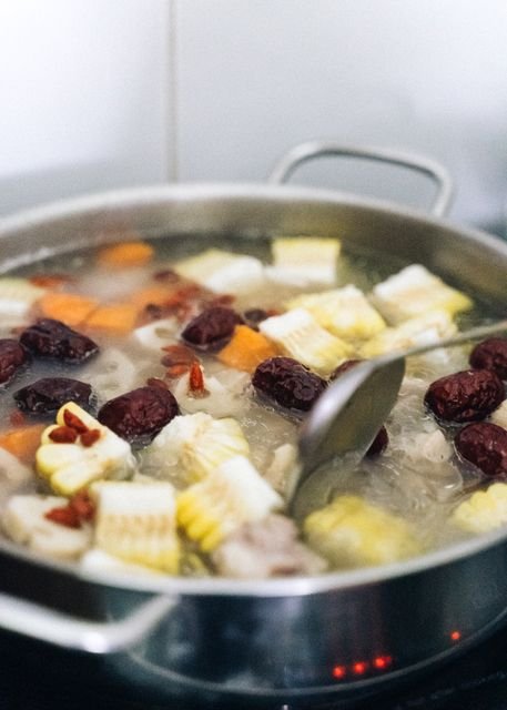 Large pot of simmering soup with vegetables and a ladle