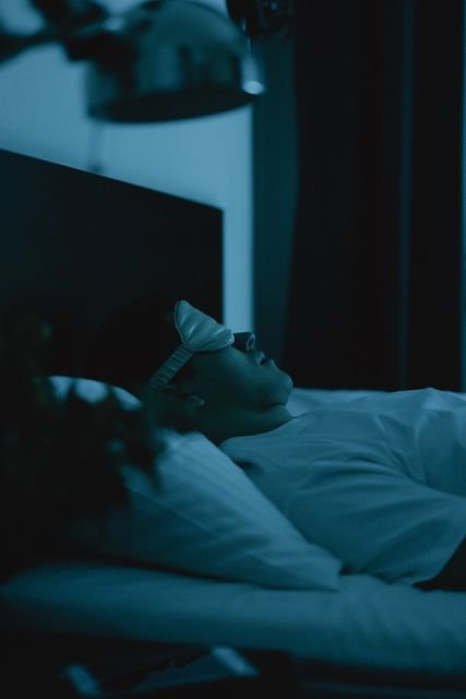Man sleeping in bed while wearing a sleep mask