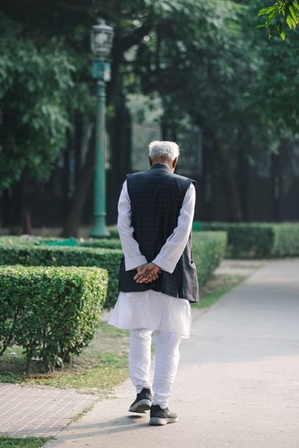 Older man walking along a path through a peaceful park