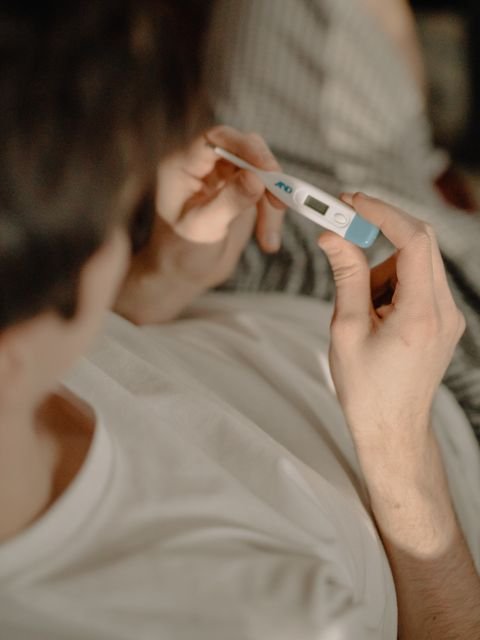 Person checking body temperature with a digital thermometer