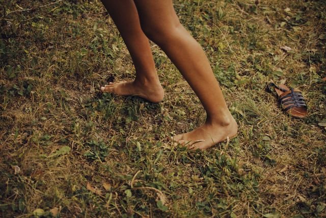 The Science of Earthing: What Grounding Does to Body Voltage—and What It Hasn’t Proven 5 Person walking barefoot across dry grass