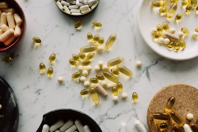 ACV Gummies vs. Liquid for Blood Sugar: Evidence, Cost, Dose, and Safety 9 Assorted pills and capsules on a marble surface