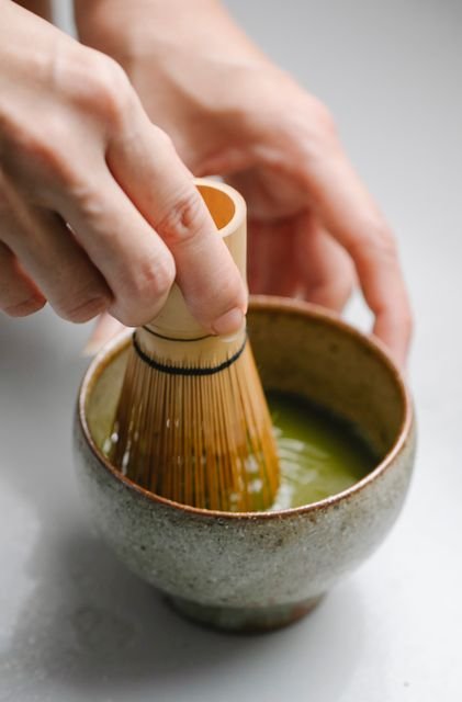 Matcha vs Coffee: Caffeine, Energy, Health Effects, Cost, and Which Fits You Better 5 Hands whisking matcha in a ceramic bowl