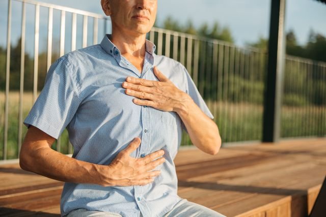 Man outdoors with hands resting on chest and abdomen
