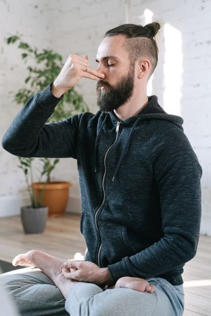 Man seated indoors practicing a calm breathing exercise