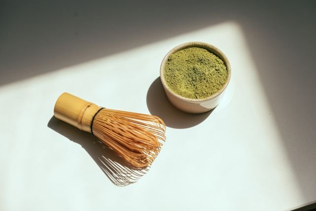 Matcha vs Coffee: Caffeine, Energy, Health Effects, Cost, and Which Fits You Better 3 Matcha powder in a bowl beside a bamboo whisk