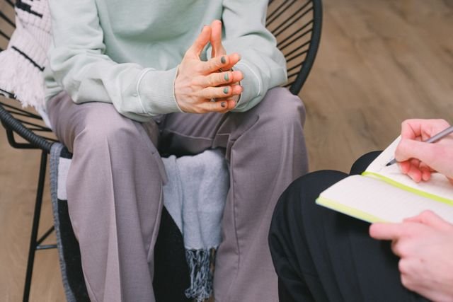 Therapist taking notes while seated across from a client