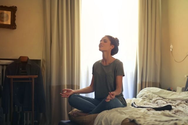 Woman sitting on a bed practicing meditation